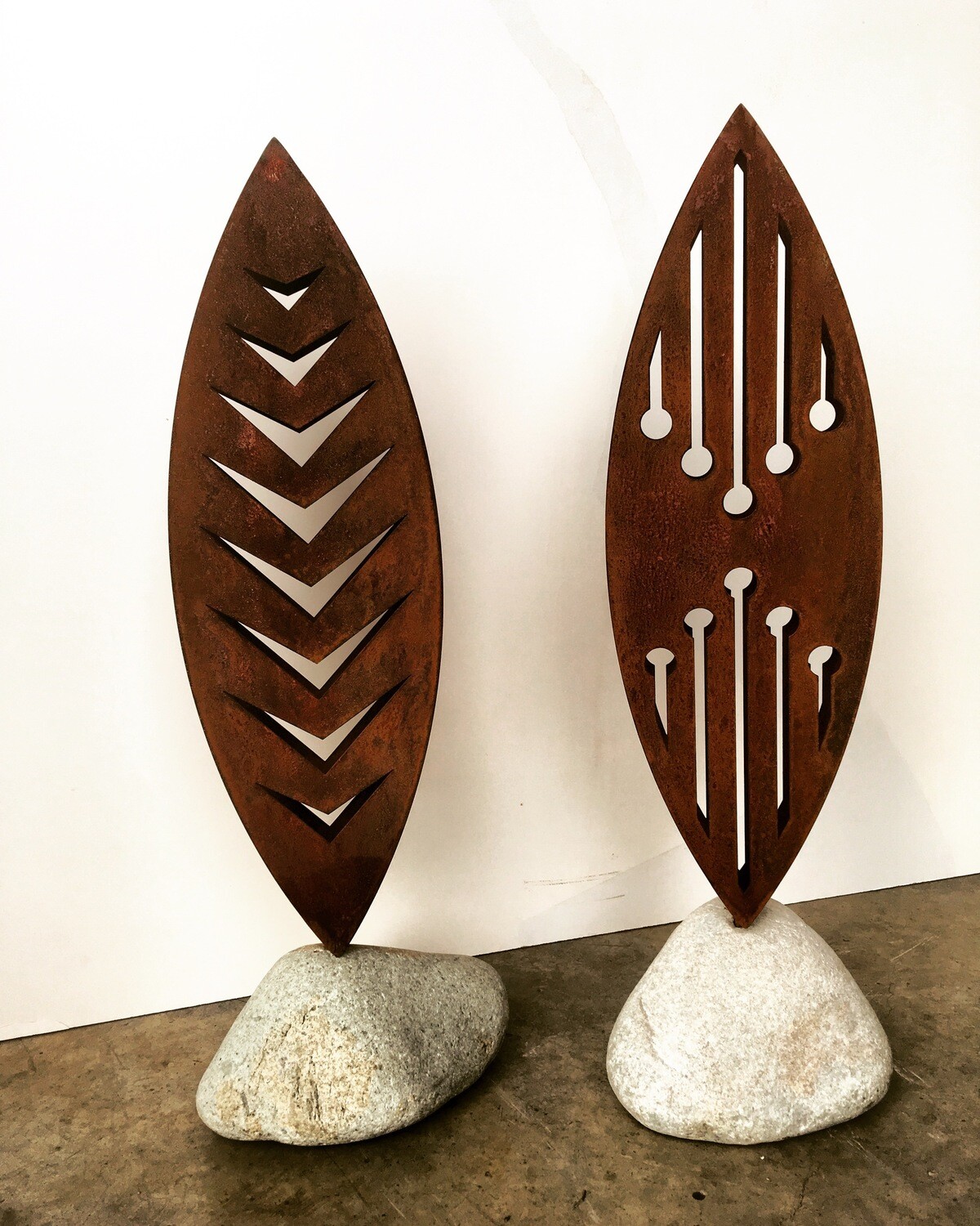 2 rusty Corten 3D sculptures in natural stone bases. Rusty Arrow and Reflection by Grounded Art NZ. South Otago, NZ