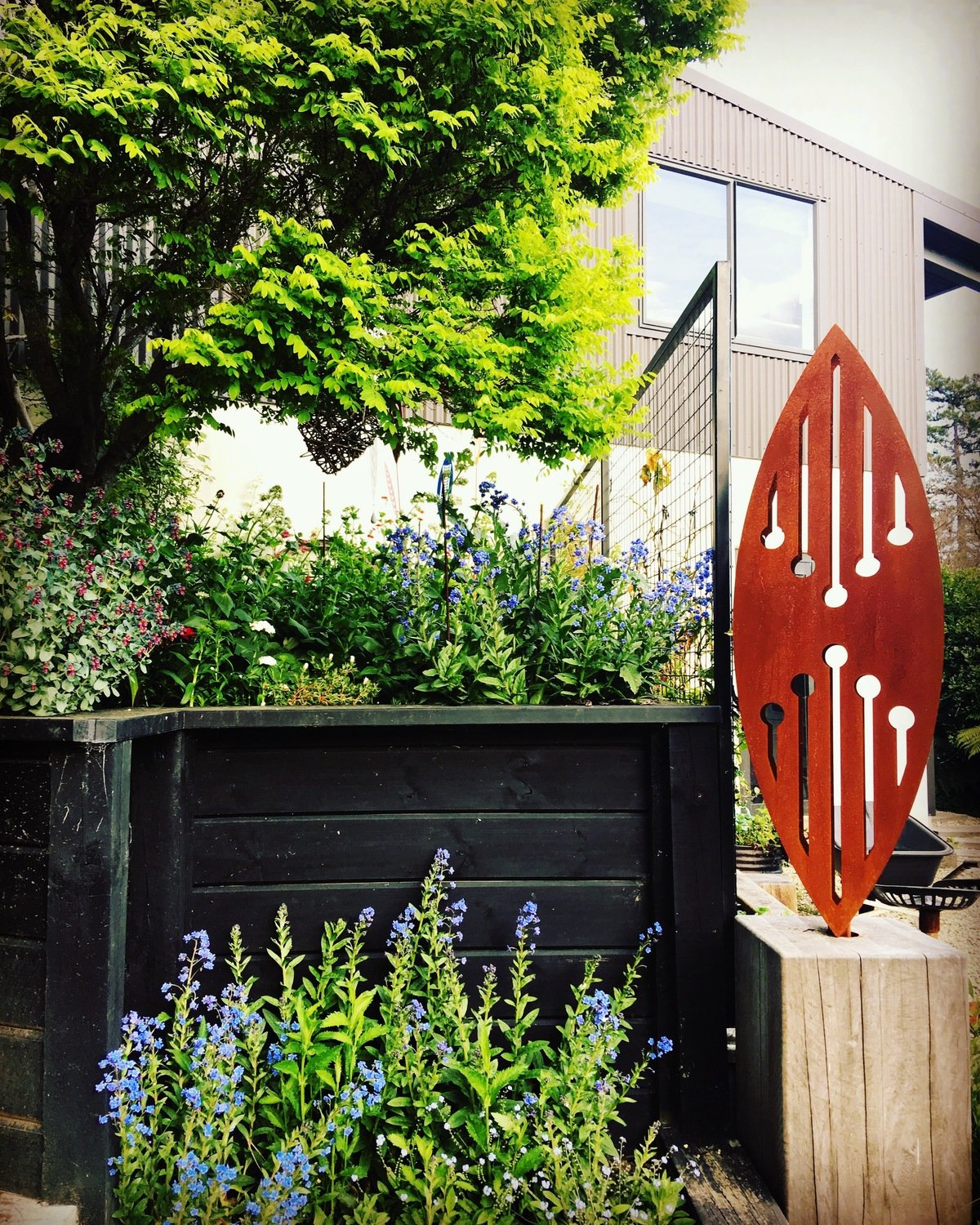 Established New Zealand garden with a rusty 3D Corten Reflection sculpture by Grounded Art NZ.