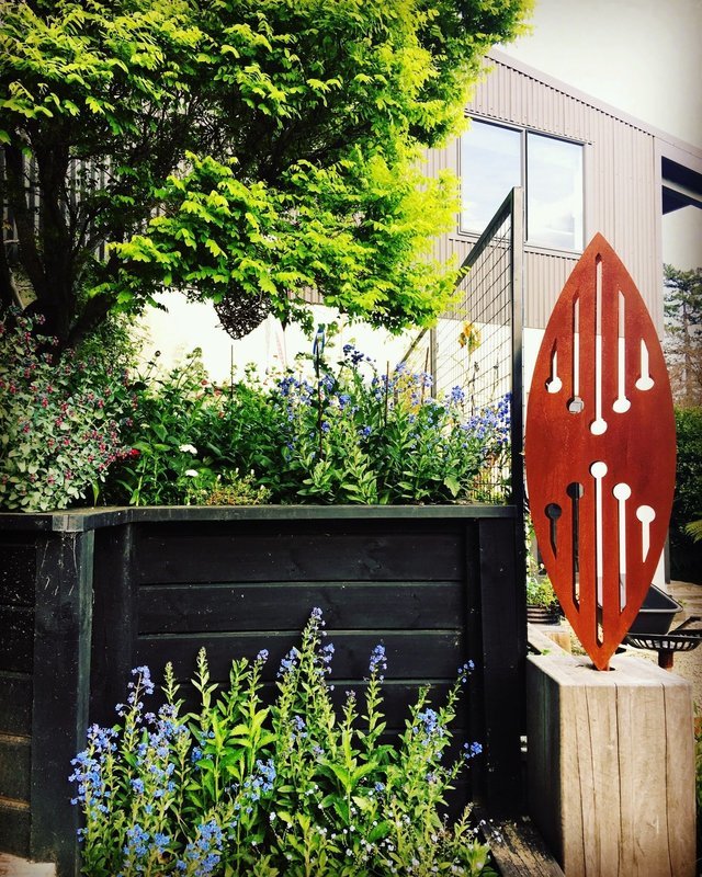 Established New Zealand garden with a rusty 3D Corten Reflection sculpture by Grounded Art NZ.