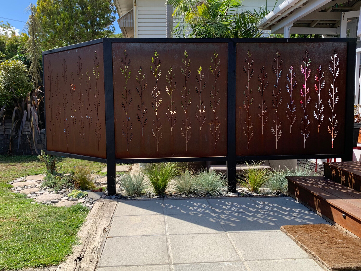 A New Zealand courtyard garden with privacy screen made from 3 Grounded Art NZ Corten Korokio screens framed in black timber.