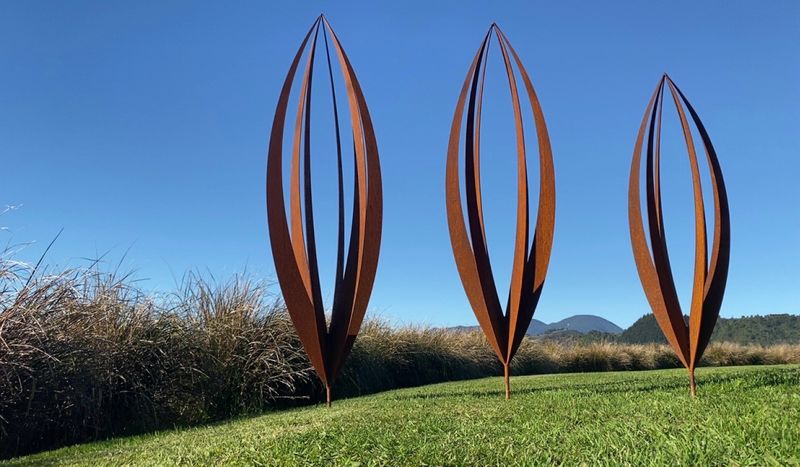 2 large Rusty Corten Pods by Grounded Art NZ on a lawn in a Native NZ garden setting.