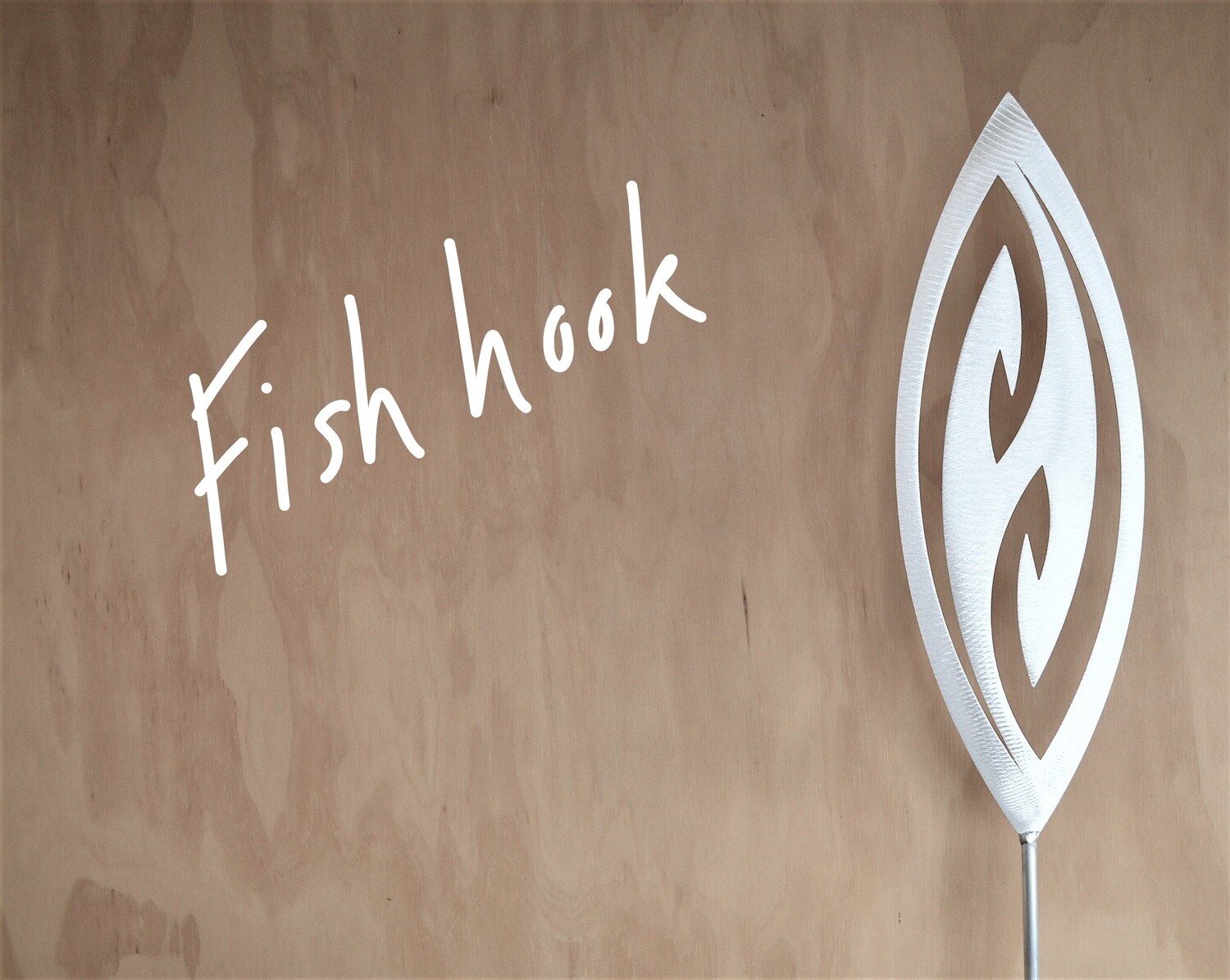Fish Hook Aluminium Spear by Grounded Art NZ in a gallery where the shadows are cast onto the pale plywood wall behind.