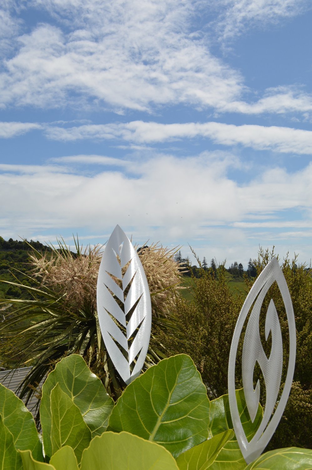 Leaf and Fish Hook designs of Alloy garden spears by Grounded Art NZ popping up in a native NZ garden. 