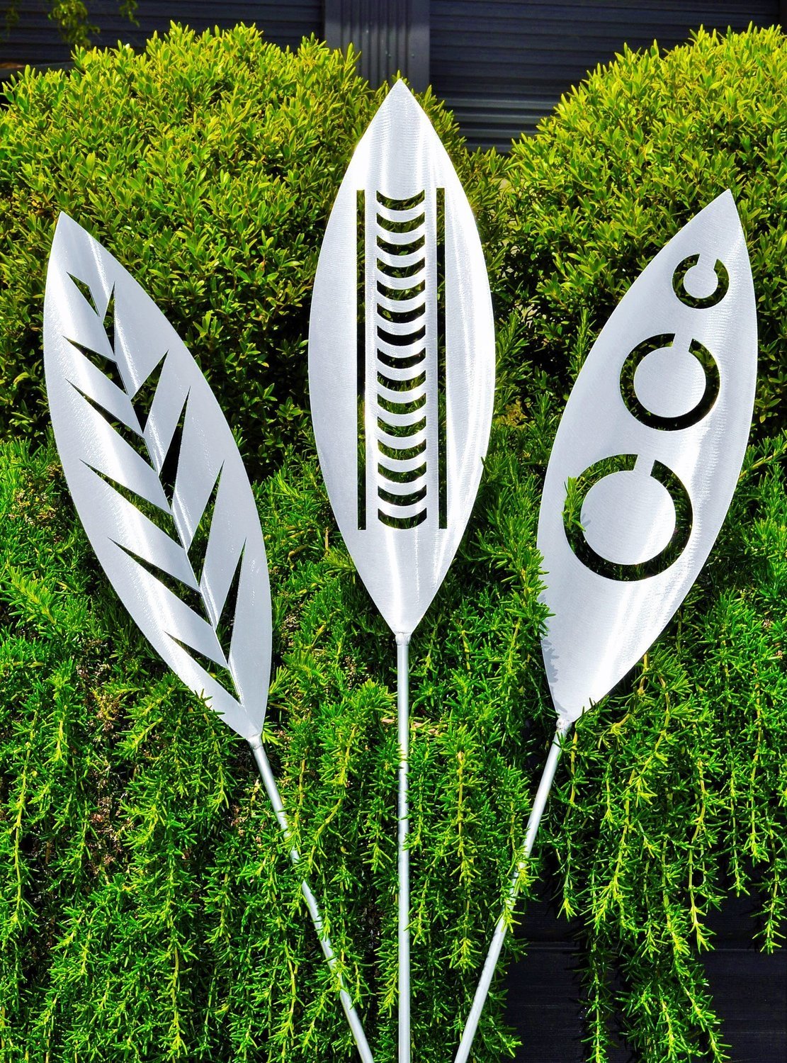 Leaf, Nikau and Tribal designs of Aluminium spears made by Grounded Art NZ in a Rosemary shrub, South Otago, New Zealand. 