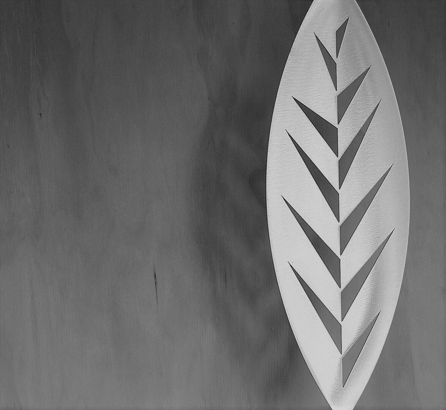Leaf Aluminium Spear by Grounded Art NZ in a gallery setting where the shadows are cast onto the pale plywood wall behind.