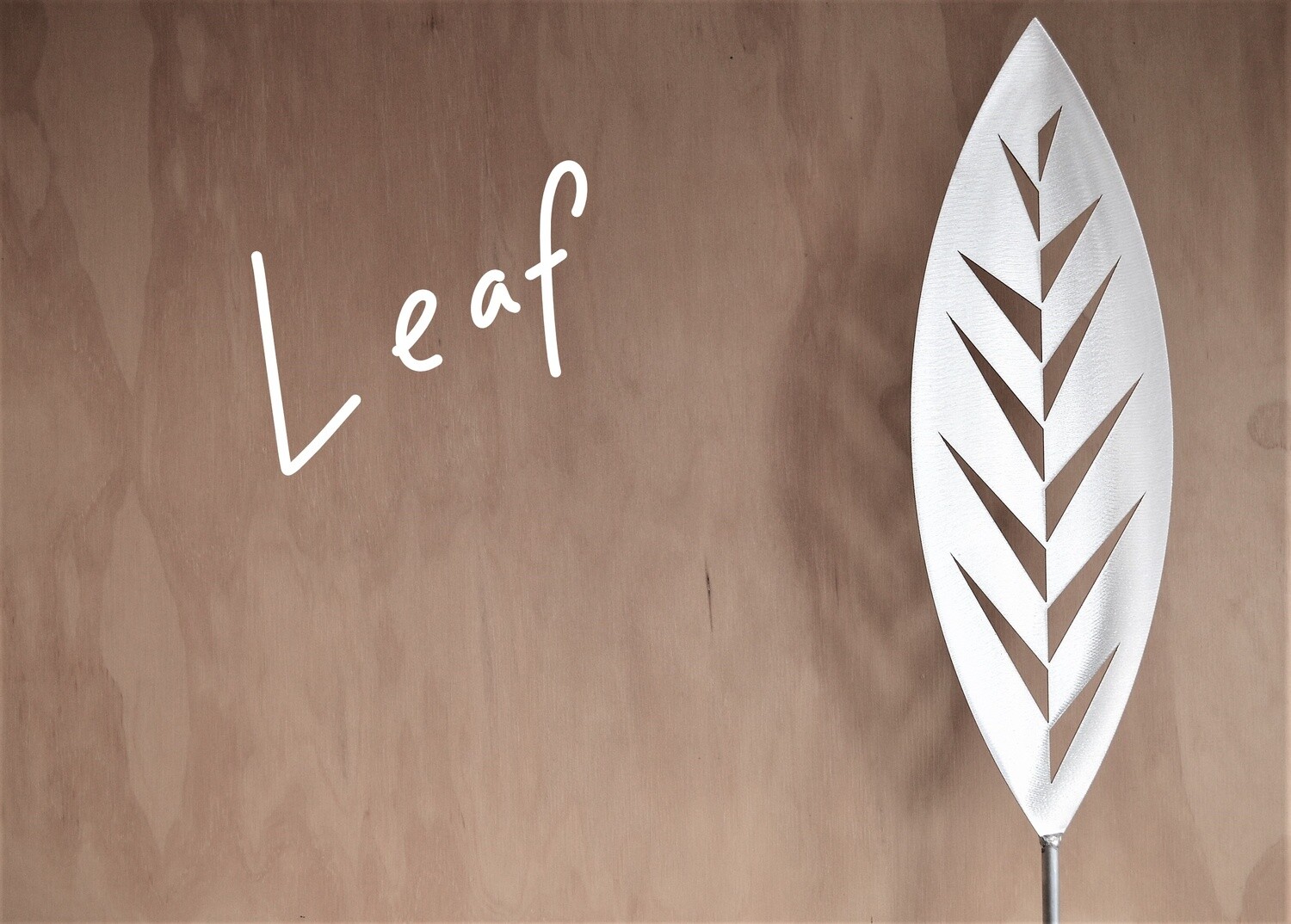 Leaf Aluminium Spear by Grounded Art NZ in a gallery setting where the shadows are cast onto the pale plywood wall behind.