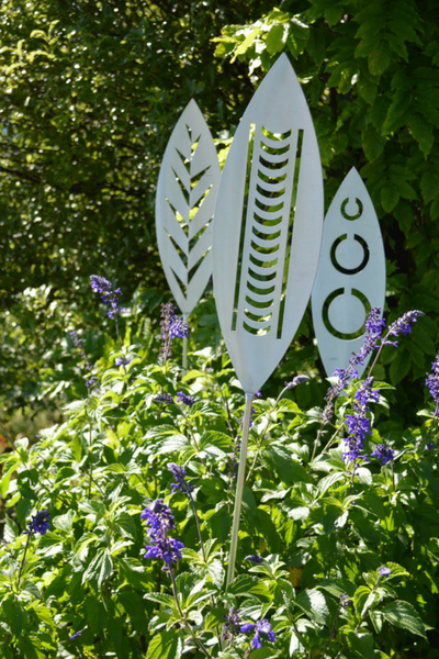 Leaf, Nikau and Tribal designs of Aluminium Garden Art Spears by Grounded Art NZ in a lush green native NZ garden. Otago, NZ.