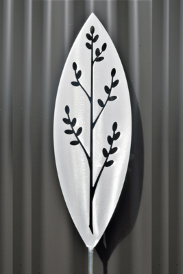 Korokio Aluminium Spear by Grounded Art NZ and a dark clad building. The bright metal art pops against the dark background.