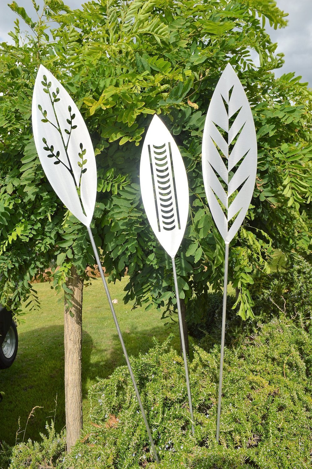 Korokio, Nikau and Leaf designs of Aluminium Garden Spear by Grounded Art NZ in front of lush landscaping in a NZ garden.