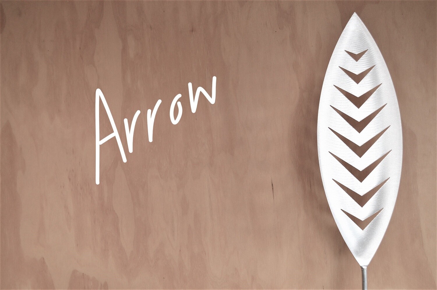 Arrow Aluminium Spear by Grounded Art NZ in a gallery setting where the shadows are cast onto the pale plywood wall behind.