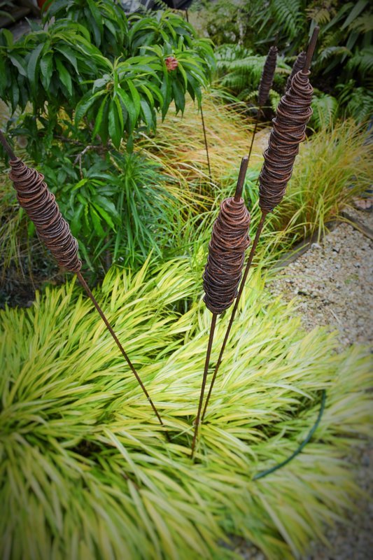 3 hand made rusty raupo by Grounded Art NZ. The rusty patina providing contrast against the green garden foliage. 