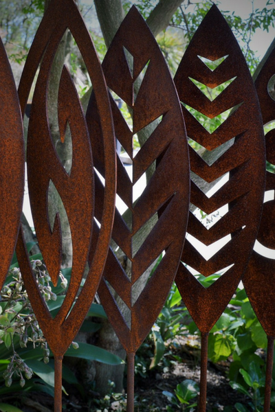 close up designs of Corten garden spear by Grounded Art NZ in a lush native NZ garden.