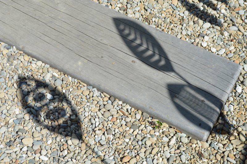 Shadow effects from Tribal, Arrow &amp; Nikau Corten garden spears by Grounded Art NZ cast on paving pebbles and wooden pavers.