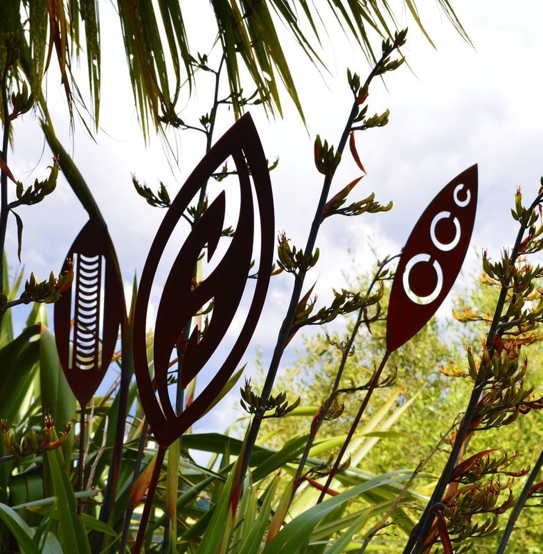 3 Corten Garden spears by Grounded Art NZ in a lush NZ native garden. The spears are our Nikau, Fish Hook and Tribal designs.
