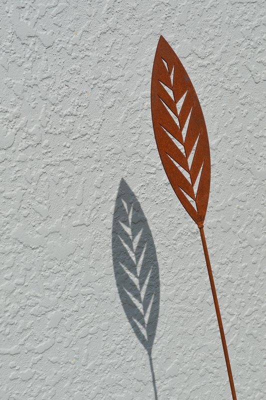 Shadows created by Grounded Art NZ Corten garden spear in Leaf design. Bright patina of the Corten against light background.