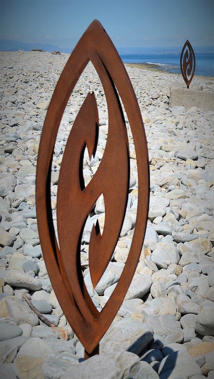 Close up of Corten Fish Hook by Grounded Art NZ at the Nelson Boulder bank, Nelson NZ. Natural stone and rusty patina.  