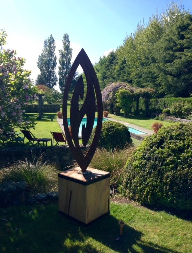 Grounded Art NZ Corten Fish Hook displayed at the Art in a Garden event in Hawarden. Corten Steel art in a macrocarpa base. 