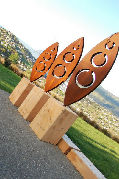 Trio of Tribal 3D Sculptures by Grounded Art NZ. Rusty Corten patina is bright and bold with a city scape and lawn behind.