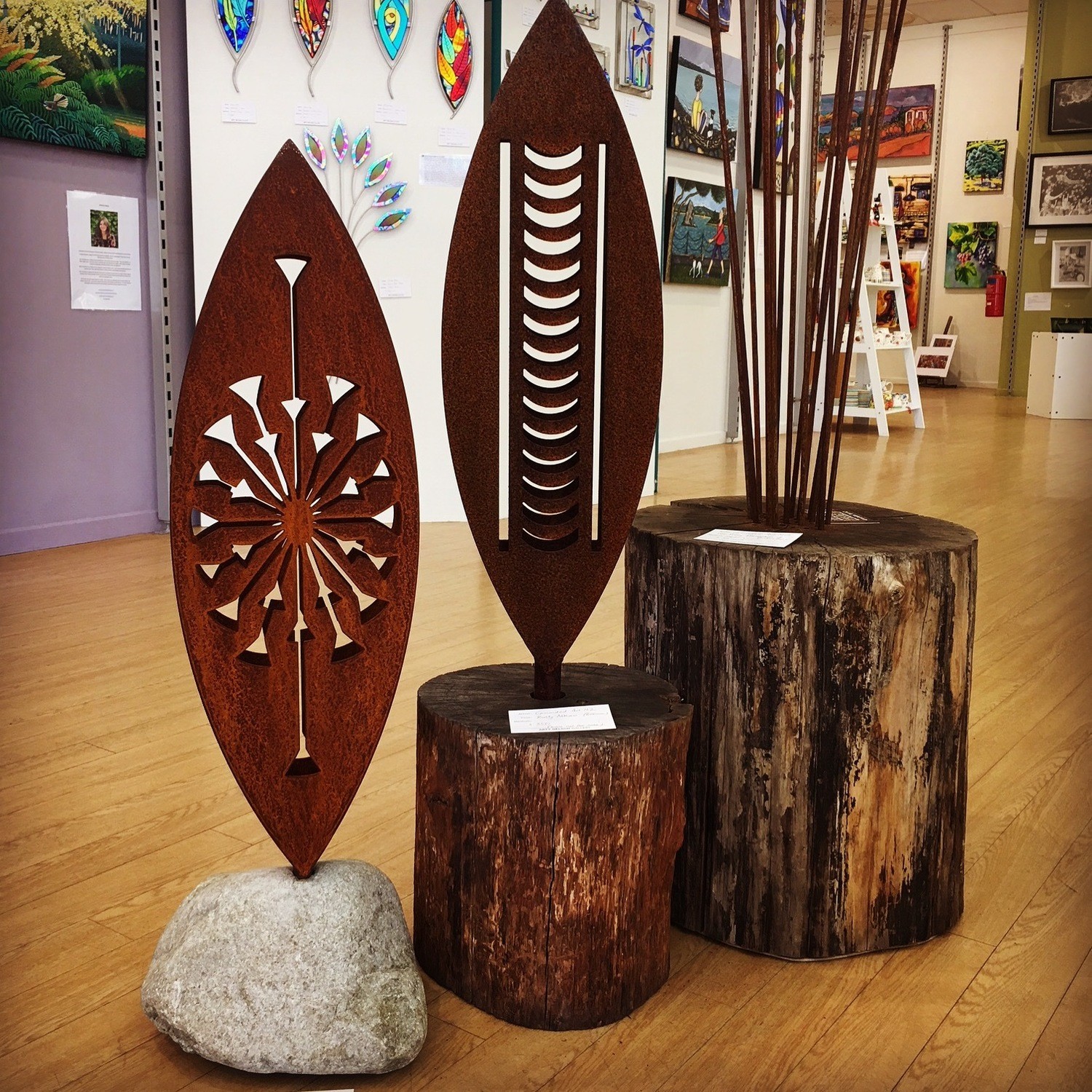 2 side by side 3D Corten Sculptures by Grounded Art NZ at Arty Nelson Gallery. Tohu in stone base and Nikau design in a log.