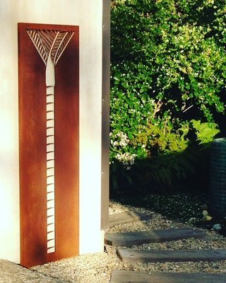 Tall Corten Nikau Panel (1845mm tall) by Grounded Art NZ on a garden wall within a Native NZ garden.