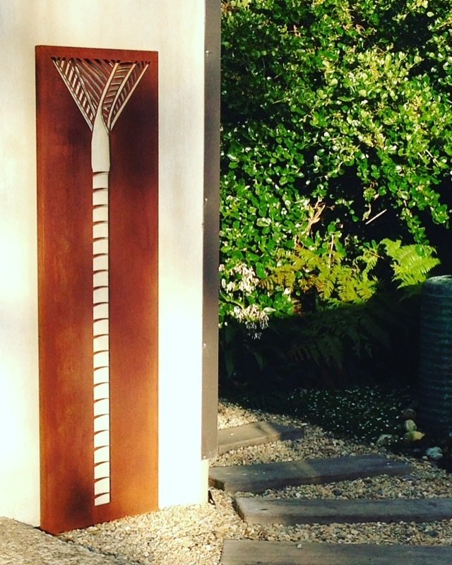 Tall Corten Nikau Panel (1845mm tall) by Grounded Art NZ on a garden wall within a Native NZ garden.