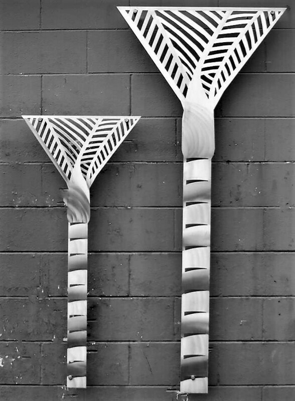 Aluminium Nikau Palm Wall Art by Grounded Art NZ. Striking pair of palms, 1200mm and 1700mm against a raw, block work wall.
