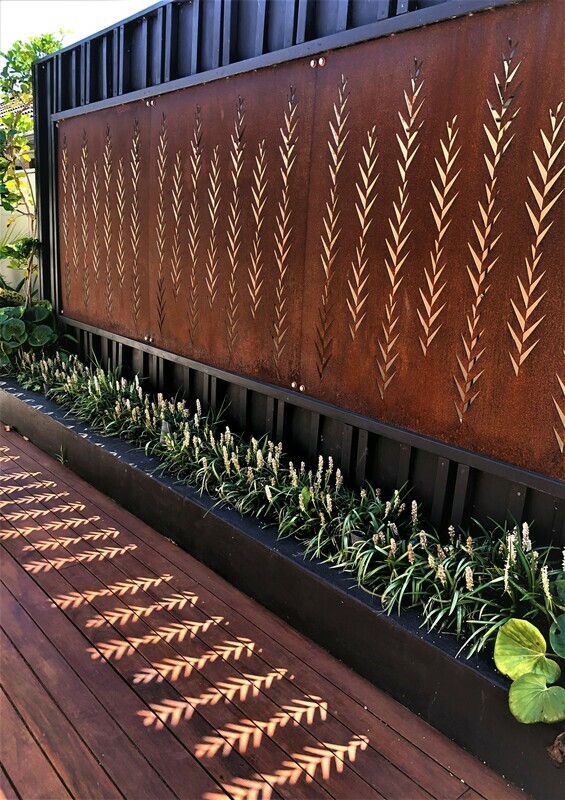 Corten Leaf screens by Grounded Art NZ. Rusty patina privacy screen letting light through onto a timber deck. 