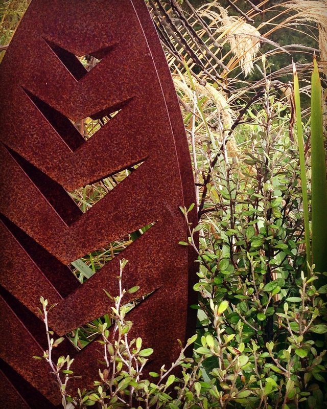 3D Corten Arrow Sculpture by Grounded Art NZ. Warm rusty hue of the steel contrast against the lush native NZ garden.