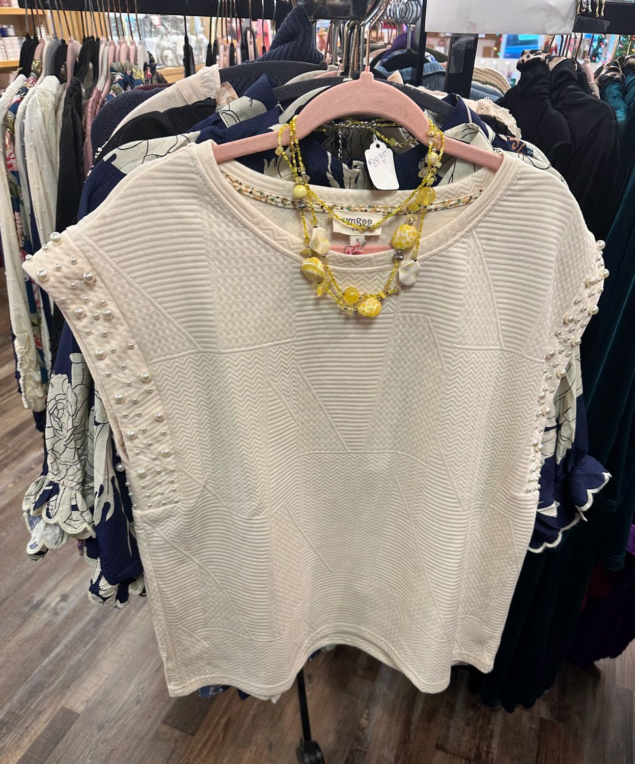 Umgee Ladies Sleeveless Pearl Blouse on a rack at Merle Norman Elizabethton. 