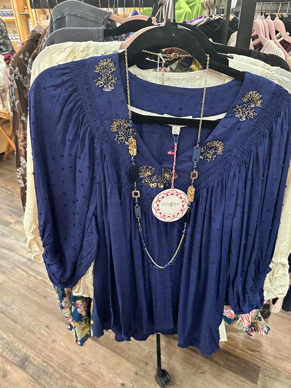 Umgee Deep Blue Flowy Blouse on a rack at Merle Norman Elizabethton. 