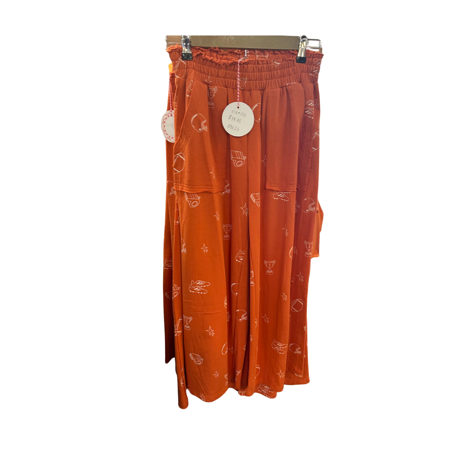 Ladies Orange Football Flowy Pants hanging on a rack in Merle Norman Elizabethton. 