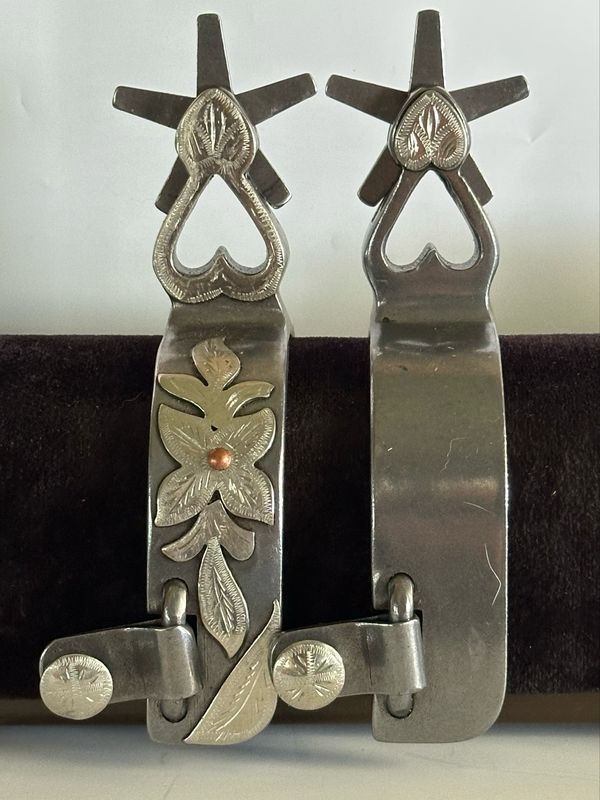 Men’s Western Spurs with a 1 1/4- inch Width Polished Steel Band with GS Floral Trim and 2 3/8- inch Length Heart Shaped Shanks with GS Trim and 5 Point Rowels 060926