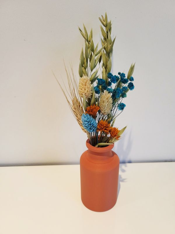 Klein terracotta vaasje gevuld met droogbloemen