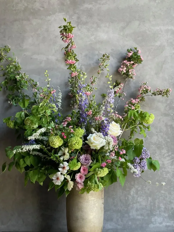 Designer's choice arrangement with pink flowering branches green viburnum white roses and purple delphinium San Francisco