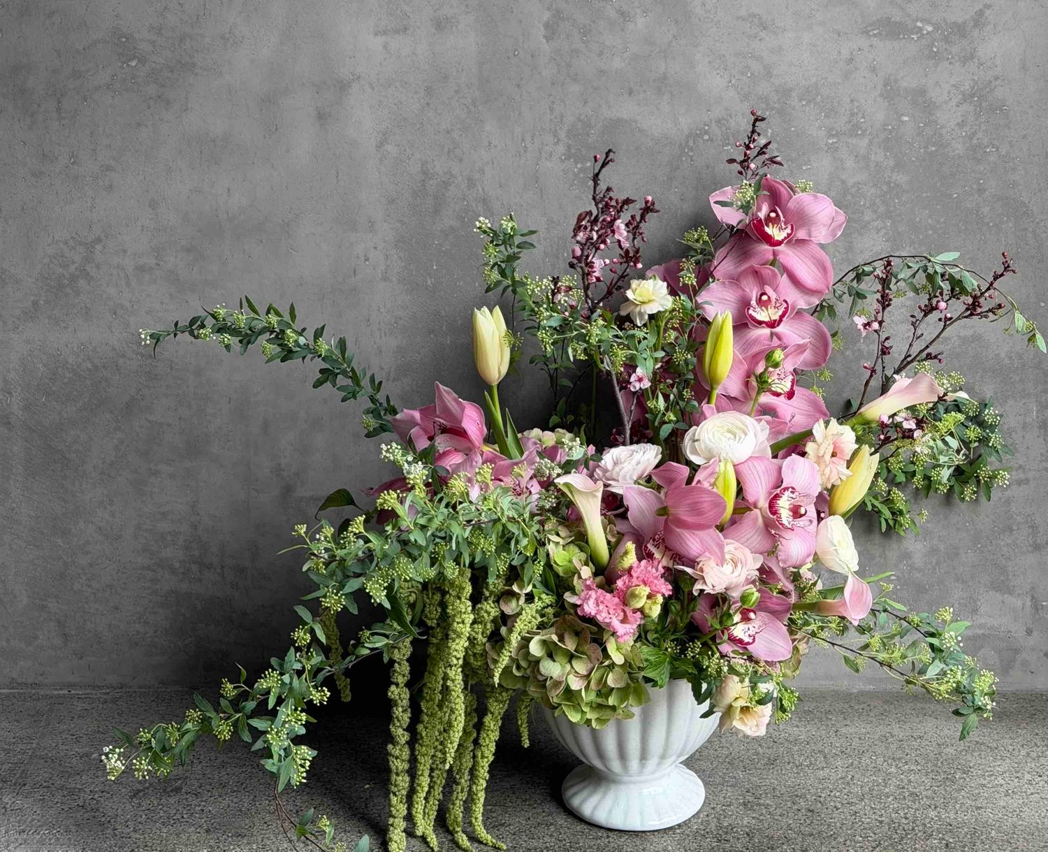 Mother's Day statement arrangement with pink orchids, tulips, amaranthus, and hydrangea in a white footed vase by Le Bouquet