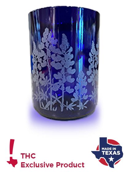 Bluebonnet Wine Bottle Glass A blue glass with bluebonnets etched into the side. Bottom of image features THC logo and Made in Texas logo.