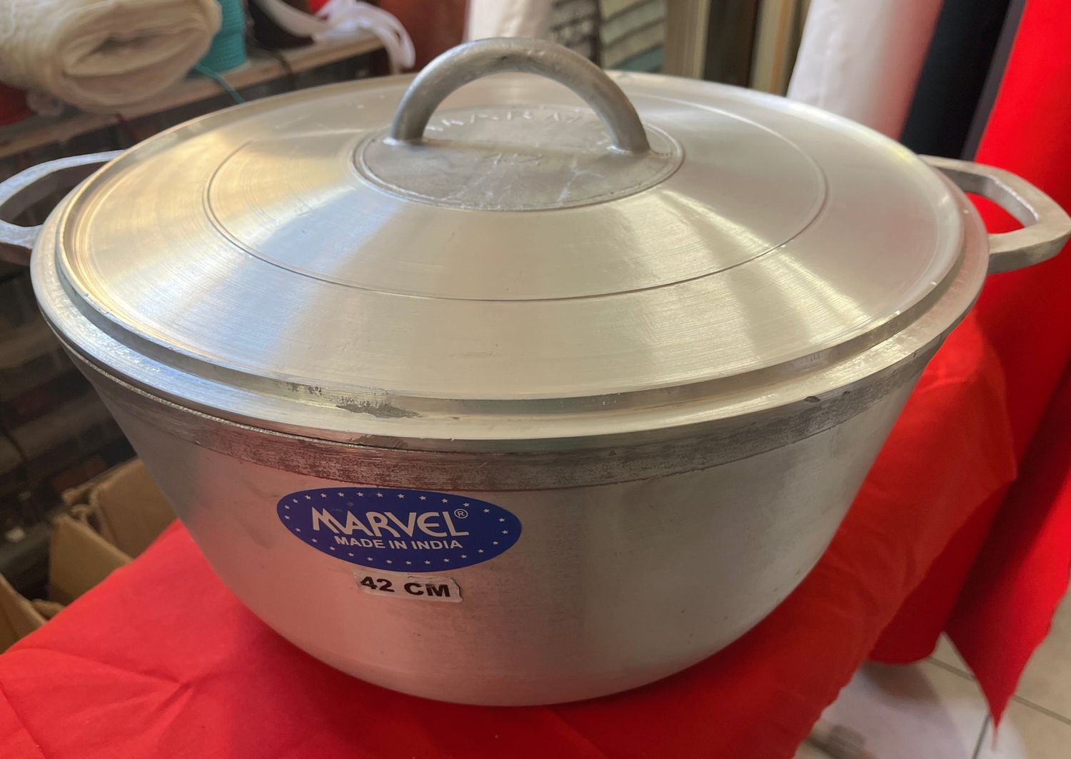 Une grande marmite en aluminium argenté avec couvercle, munie de poignées des deux côtés.