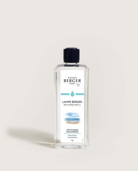 A bottle of Maison Berger Ocean Breeze fragrance refill. Clear liquid, blue cap, and a beach scene …