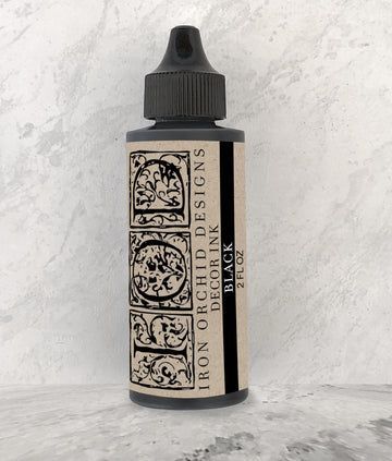 Black ink bottle with decorative label against a mottled background.