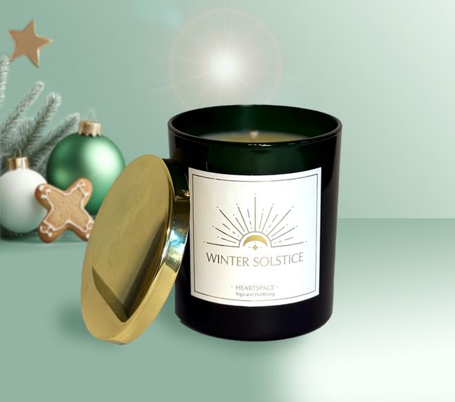 Product shot of HeartSpace 'Winter Solstice' luxury 30cl candle in luxury green glass with gold lid on festive background.