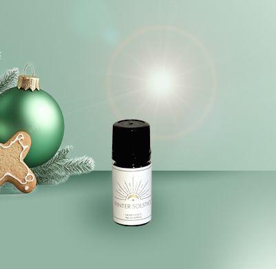 Product shot of HeartSpace 'Winter Solstice' pure essential oils in 5ml amber bottle on festive background.