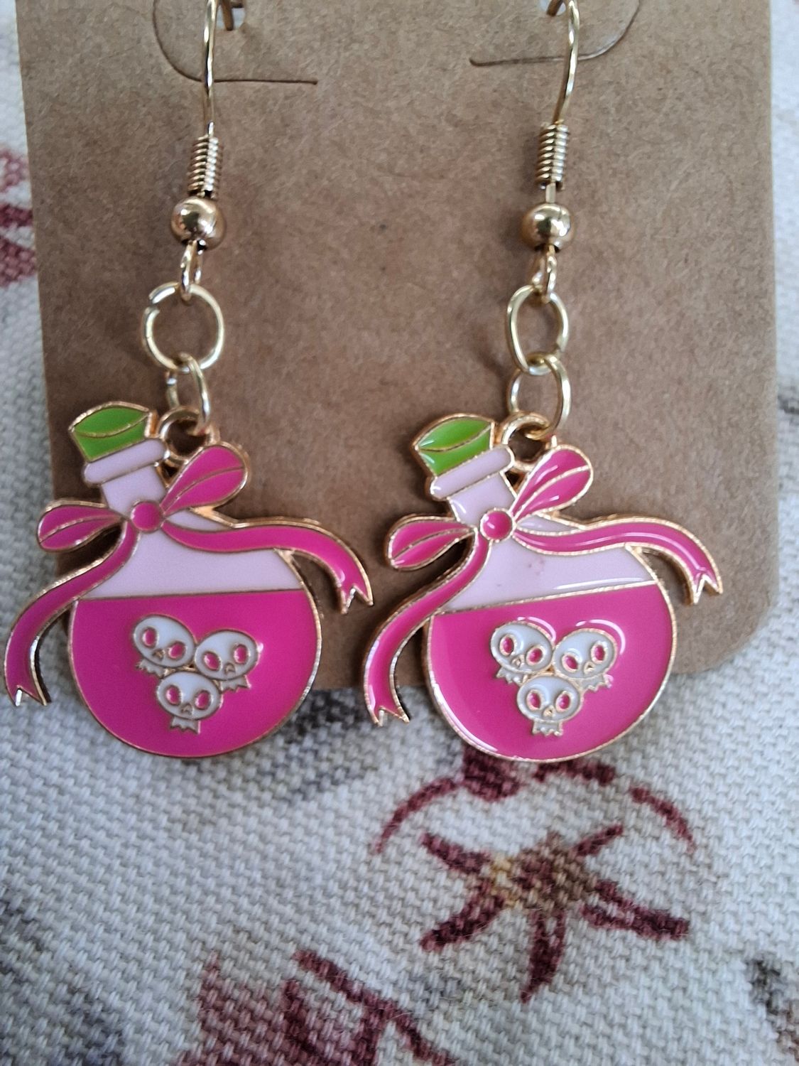 Pink Potion Halloween earrings with skulls on gold