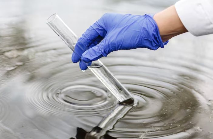main avec un gant bleu qui teste l'eau