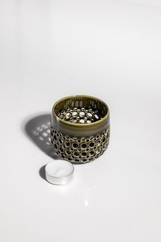 Patterned ceramic green and cream votive candleholder designed to hold tealight candle and handmade by artisans.