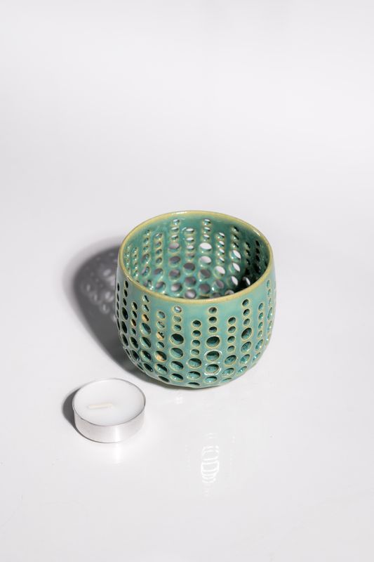 Ocean blue ceramic candleholder with small holes punched in for tealight candle to shine light and shadows through.