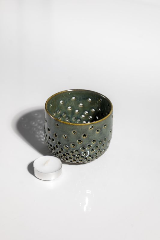 Organic green ceramic candleholder with small holes that project light with a tealight candle handmade in USA