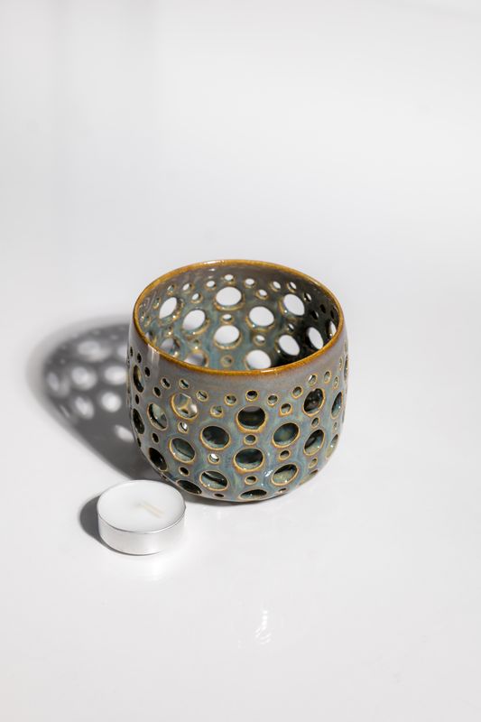 Irridescent intricate daisy pattern tealight candleholder for dining room table in contemporary home.