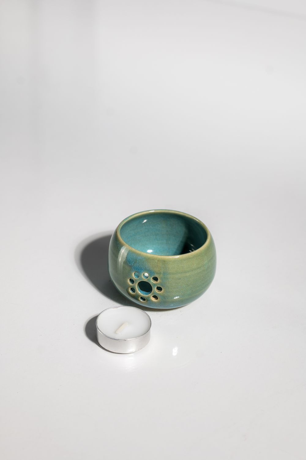 Daisy patterned ceramic candleholder with tealight candle in beach cabin blue glaze. CORTERRA