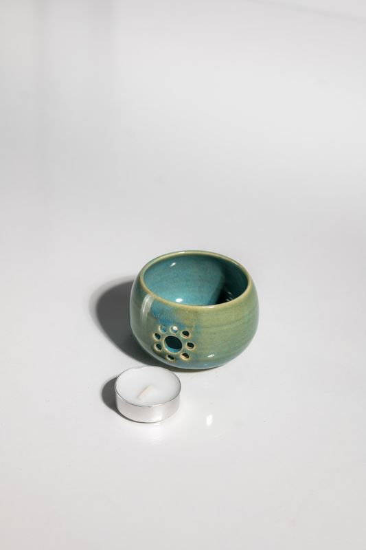 Daisy patterned ceramic candleholder with tealight candle in beach cabin blue glaze. CORTERRA