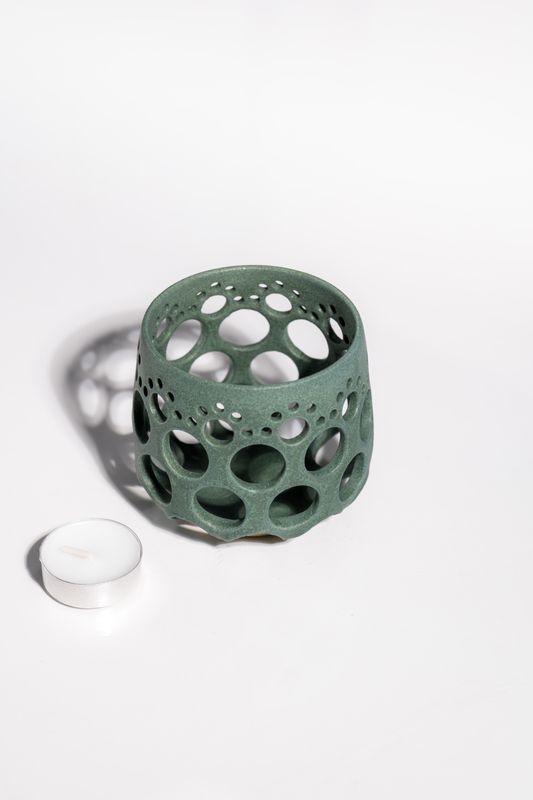 Ultra light ceramic candleholder with hand carved holes  pierced around the vessel to allow light to shine through.